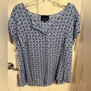 Short sleeve blue and white geometric patterned blouse.